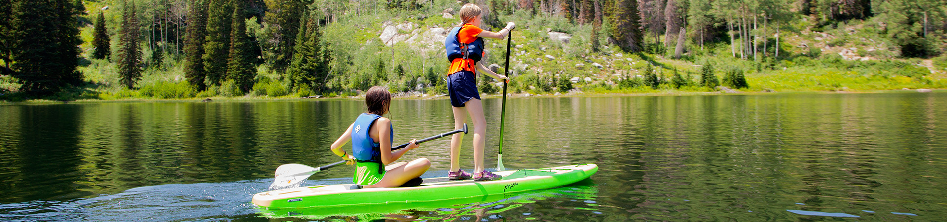  two girls kayaking across a lake 